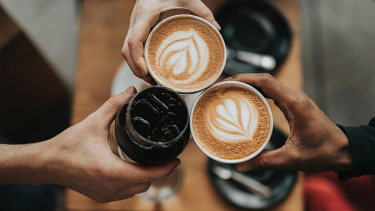 Three people with coffee drinks making a toast.