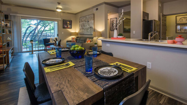 Apartment Kitchen with Stainless Steel Appliances, Dining and Living Room with wood floors.