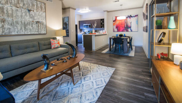 Apartment Kitchen with Stainless Steel Appliances, Dining and Living Room with wood floors.