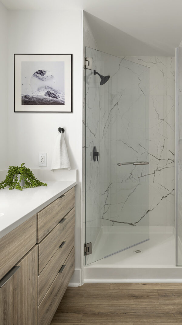 Apartment Bathroom with glass enclosed shower and hardwood flooring.