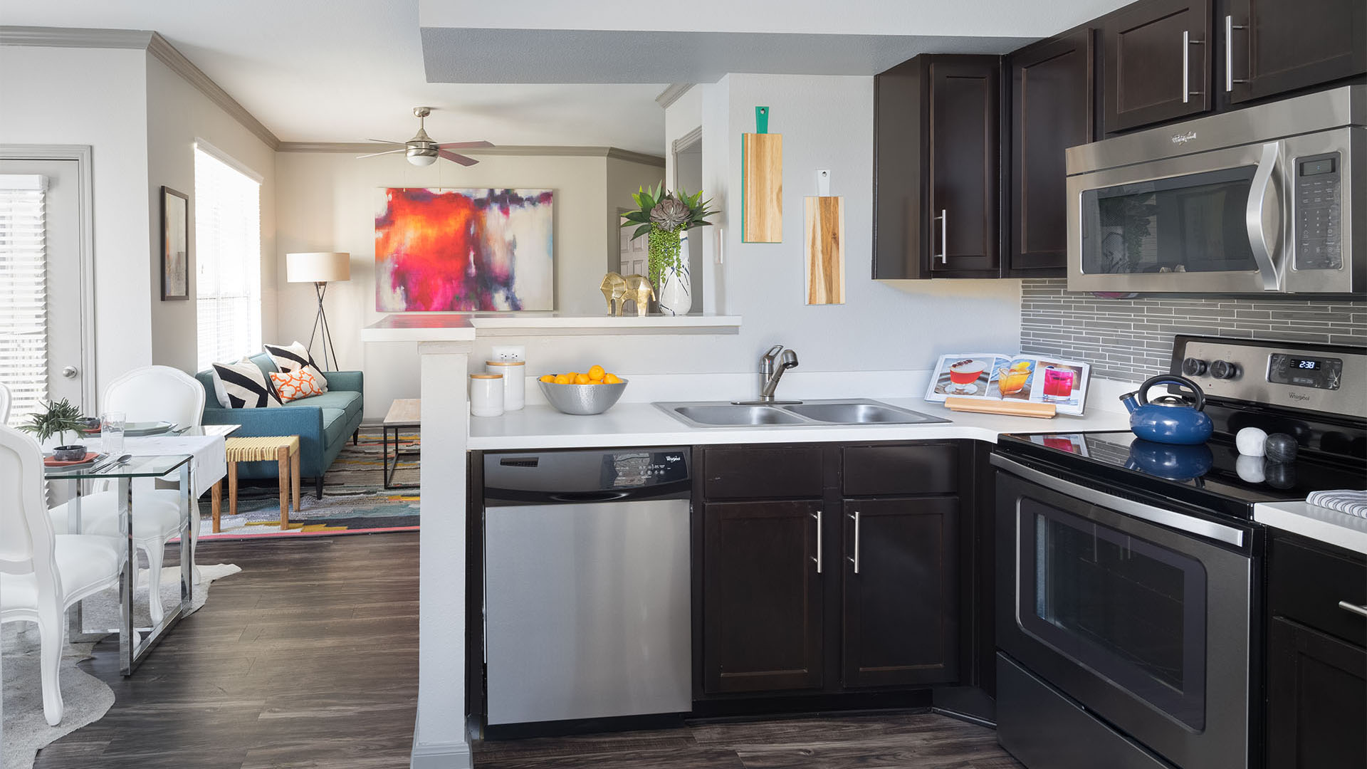 Apartment Kitchen with Stainless Steel Appliances, Dining and Living Room with wood floors.