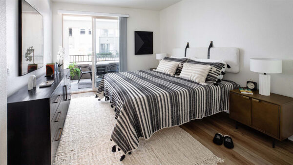 Spacious apartment bedroom with wood-style flooring and balcony access.