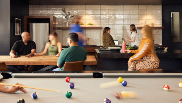 Resident lounge with people playing pool and sitting together at tables.
