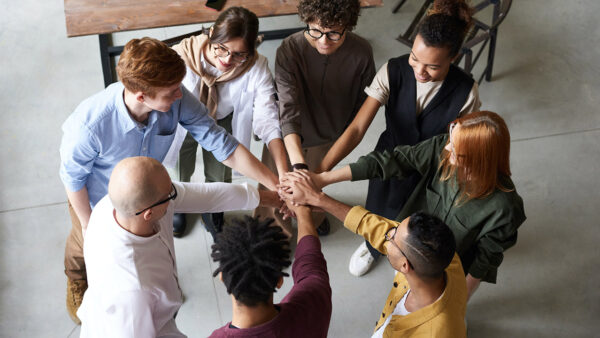 People standing in circle putting their hands together.