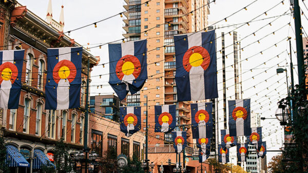 Street in Denver with string lights and Colorado flags hung across the road.