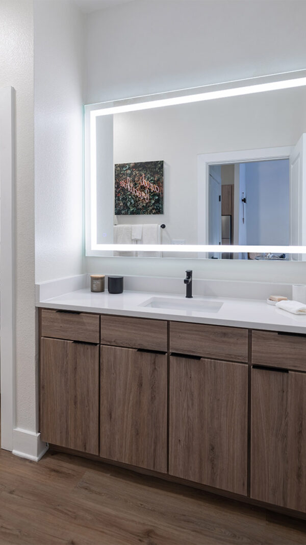 Apartment bathroom with wood-style flooring and LED vanity mirror.