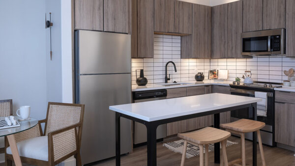 Apartment kitchen with stainless steel appliances, quartz countertops and wood-style flooring.