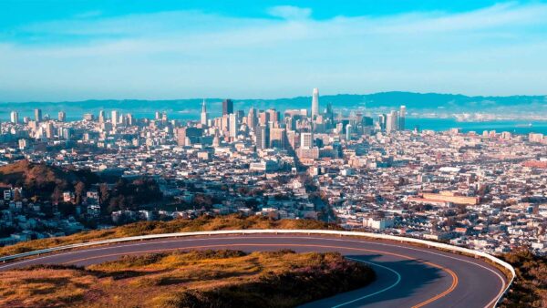 Winding mountain road high above San Jose skyline.