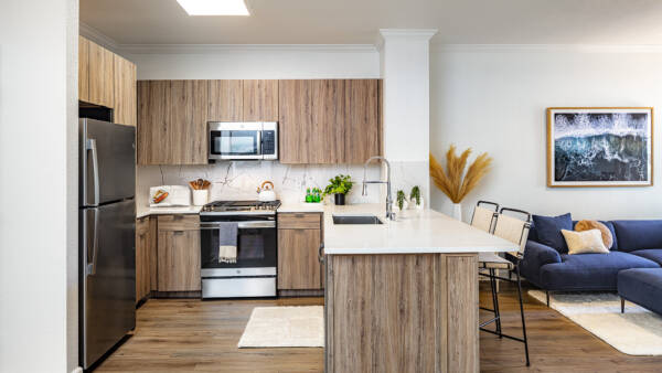 A kitchen with wood-look cabinets, stainless steel appliances, and a breakfast bar with seating.