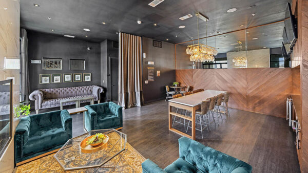 Resident lounge with plush seating, wood style floor, and large TVs.