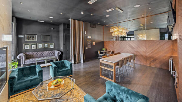 Resident lounge with plush seating, wood style floor, and large TVs.