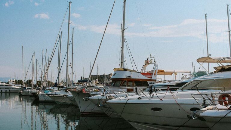 Marina with sailing yachts under cloudy skies.