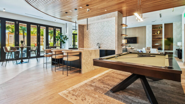 Griffis West Palm apartments resident lounge with pool table, bar with stools, and dining tables.