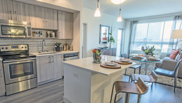 Modern luxury apartment kitchen with quartz island, stainless steel appliances, and open-concept dining and living area