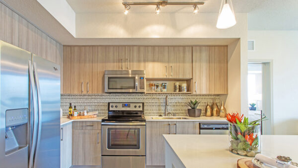 Luxury apartment kitchen with wood cabinetry, stainless steel appliances, and quartz countertops