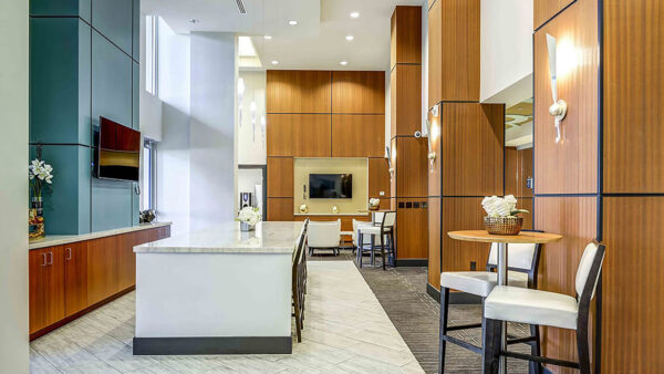 Luxury apartment resident lounge with kitchen island, bar seating, and modern fireplace