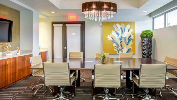 Luxury apartment community conference room with large meeting table, modern lighting, and contemporary artwork