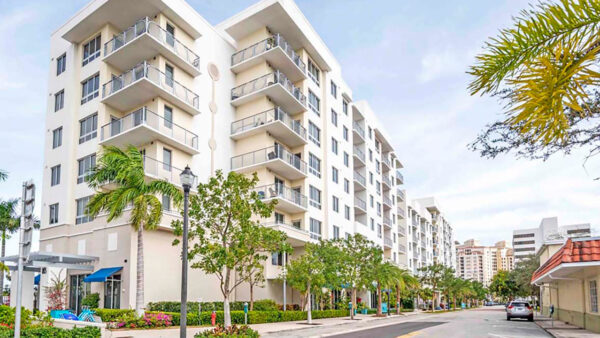 Luxury apartment community exterior with modern mid-rise building, balconies, and landscaped streetscape