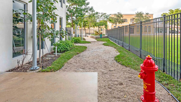 Luxury apartment community dog run with fenced pet area and landscaped walking path