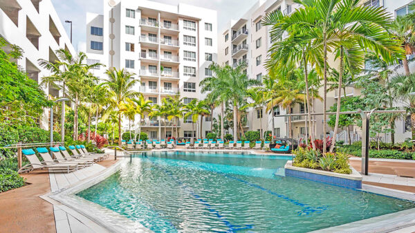 Luxury apartment resort-style pool with palm trees, sun loungers, and landscaped courtyard