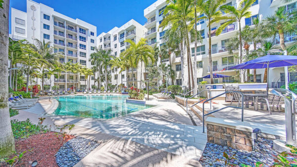 Luxury apartment resort-style pool with palm trees, sun loungers, and landscaped courtyard