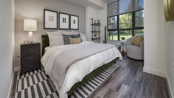 Griffis Edgemoor apartment bedroom with an upholstered bed and large windows.