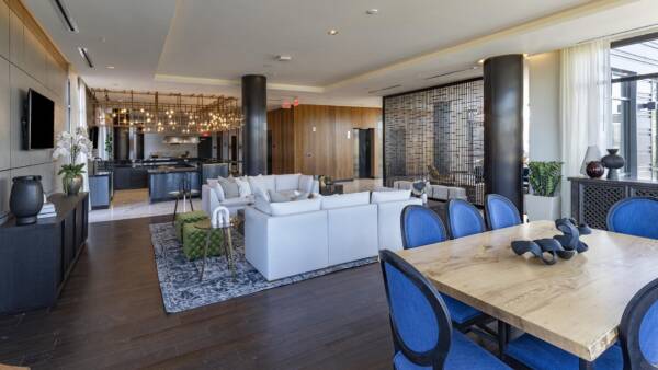 Griffis Edgemoor entertainment lounge with white sofas, blue dining chairs, and a community table.