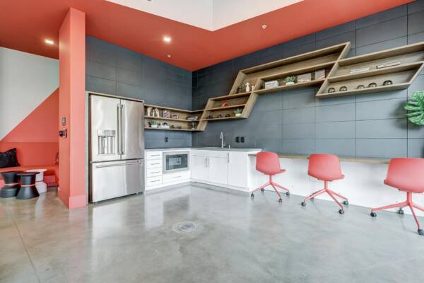 Griffis Platinum Triangle business center with a coral accent wall, counter seating, and red chairs.