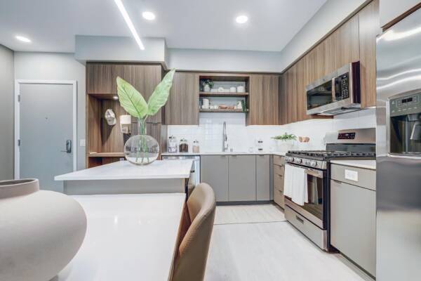 Griffis Platinum Triangle two-bedroom apartment kitchen with wood cabinetry, quartz counters, and stainless steel appliances.
