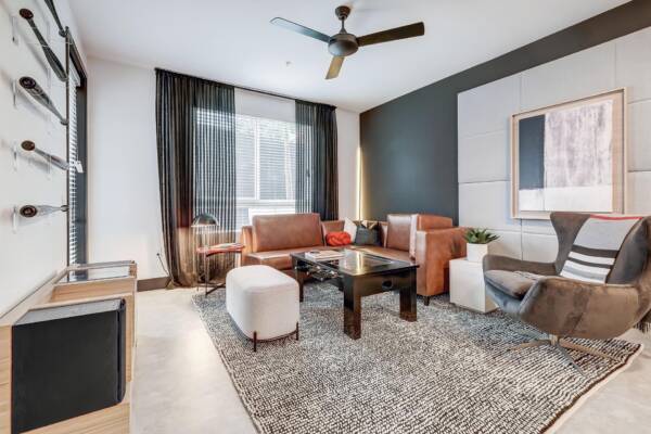 Griffis Platinum Triangle one-bedroom apartment living room with leather seating and a ceiling fan.