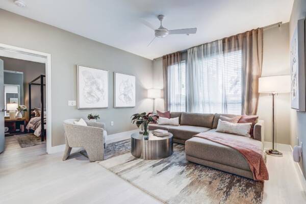 Griffis Platinum Triangle two-bedroom apartment living room with a sectional sofa and sheer window curtains.