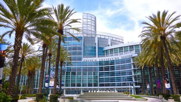 Anaheim Convention Center glass facade framed by palm trees.
