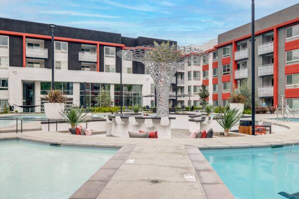 Griffis Platinum Triangle pool courtyard with a central walkway, cabanas, and a sculptural tree.