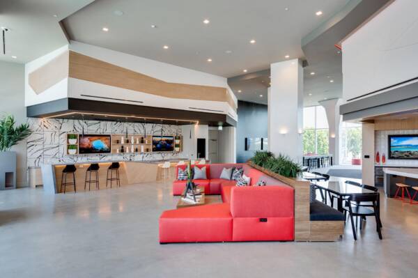 Griffis Platinum Triangle resident lounge with red sofas, bar seating, and a TV wall.
