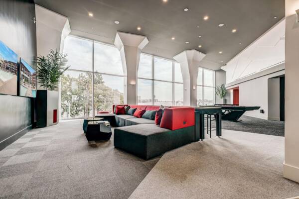 Griffis Platinum Triangle resident lounge with red sectional seating, a billiards table, and floor-to-ceiling windows.
