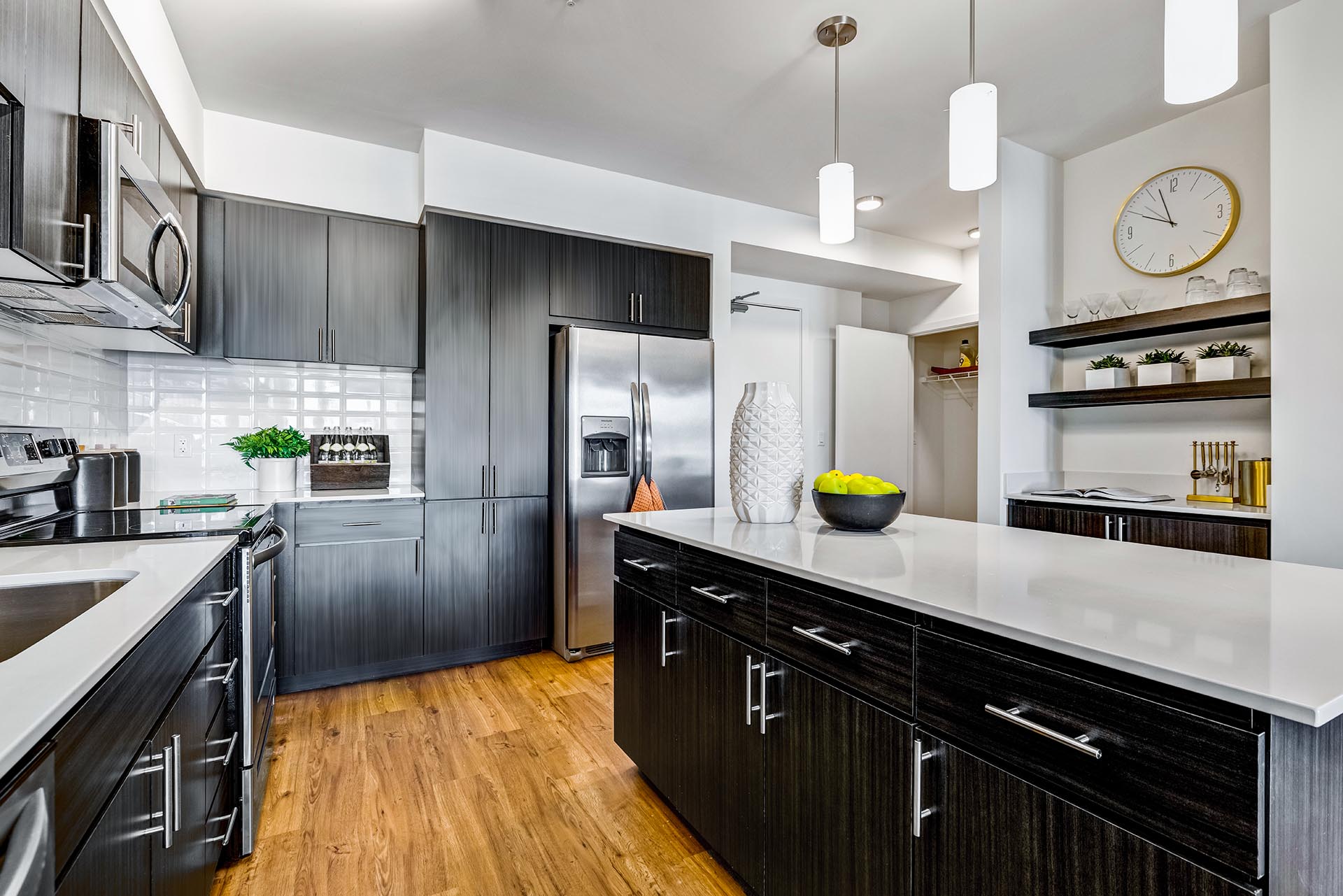 Griffis Shoreline apartment kitchen with dark cabinetry, stainless steel appliances, and pendant lighting.