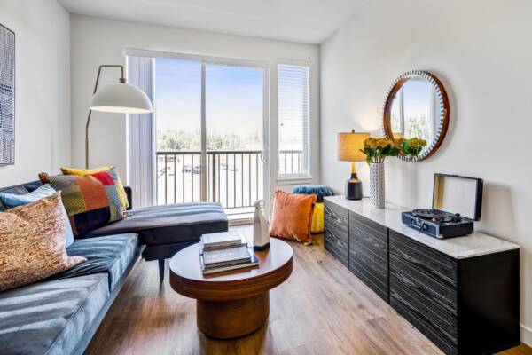 Griffis Shoreline apartment living room with sofa, round mirror, and large windows.