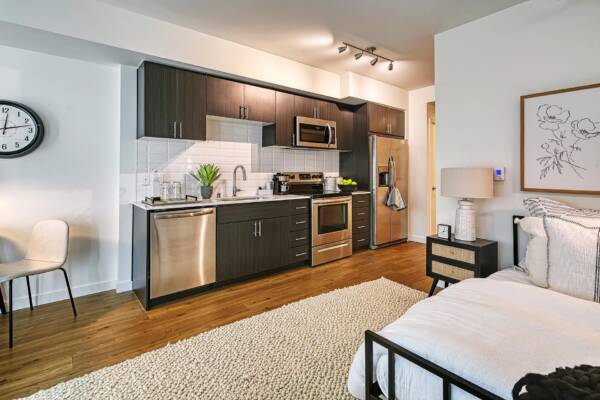Griffis Shoreline studio apartment kitchen with dark cabinetry and stainless steel appliances.