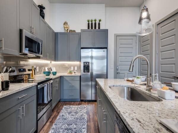 Apartment kitchen with wood style floor and stainless steel appliances.