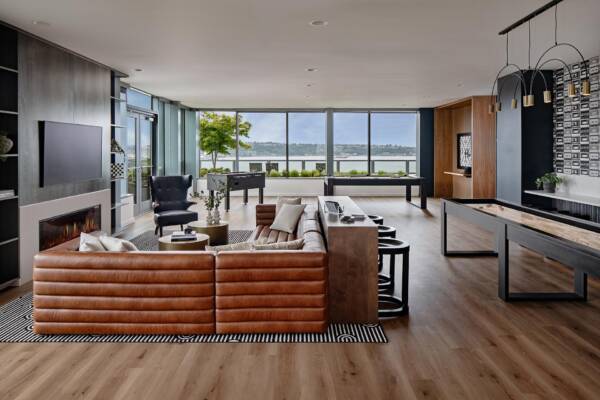 Griffis Seattle Waterfront entertainment lounge with leather sectional, fireplace, and shuffleboard table