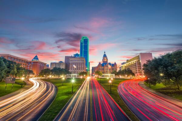 Downtown Dallas skyline at dusk with light trails on the highway