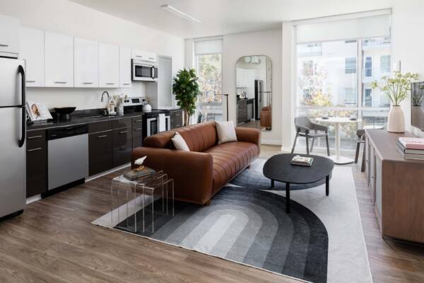 Griffis East Village apartment living room and kitchen with wood style floor and stainless steel appliances in San Diego, CA.