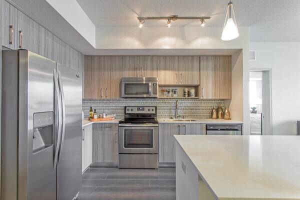 Griffis North Olive apartment kitchen with wood style floor and stainless steel appliances.